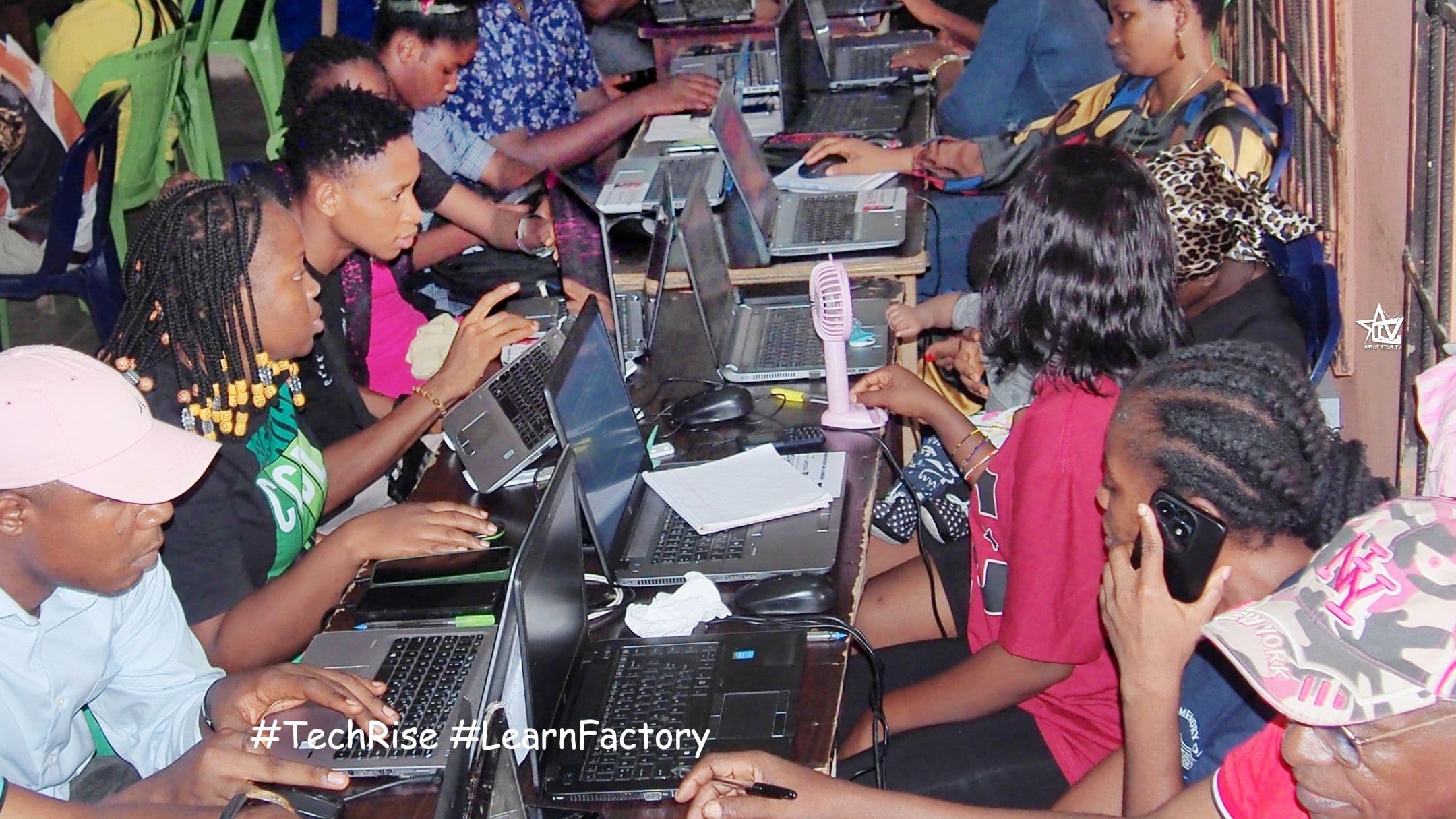 TechRise trainees working on laptops in a busy classroom